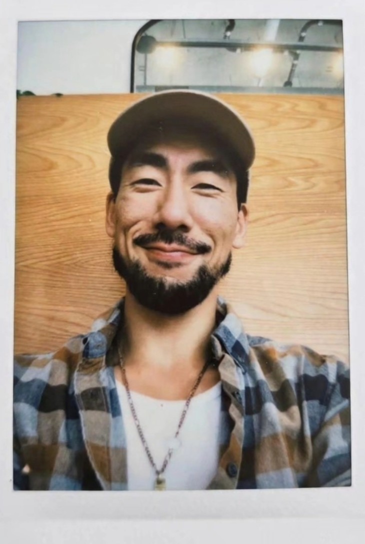 Janū smiling in a blue plaid shirt